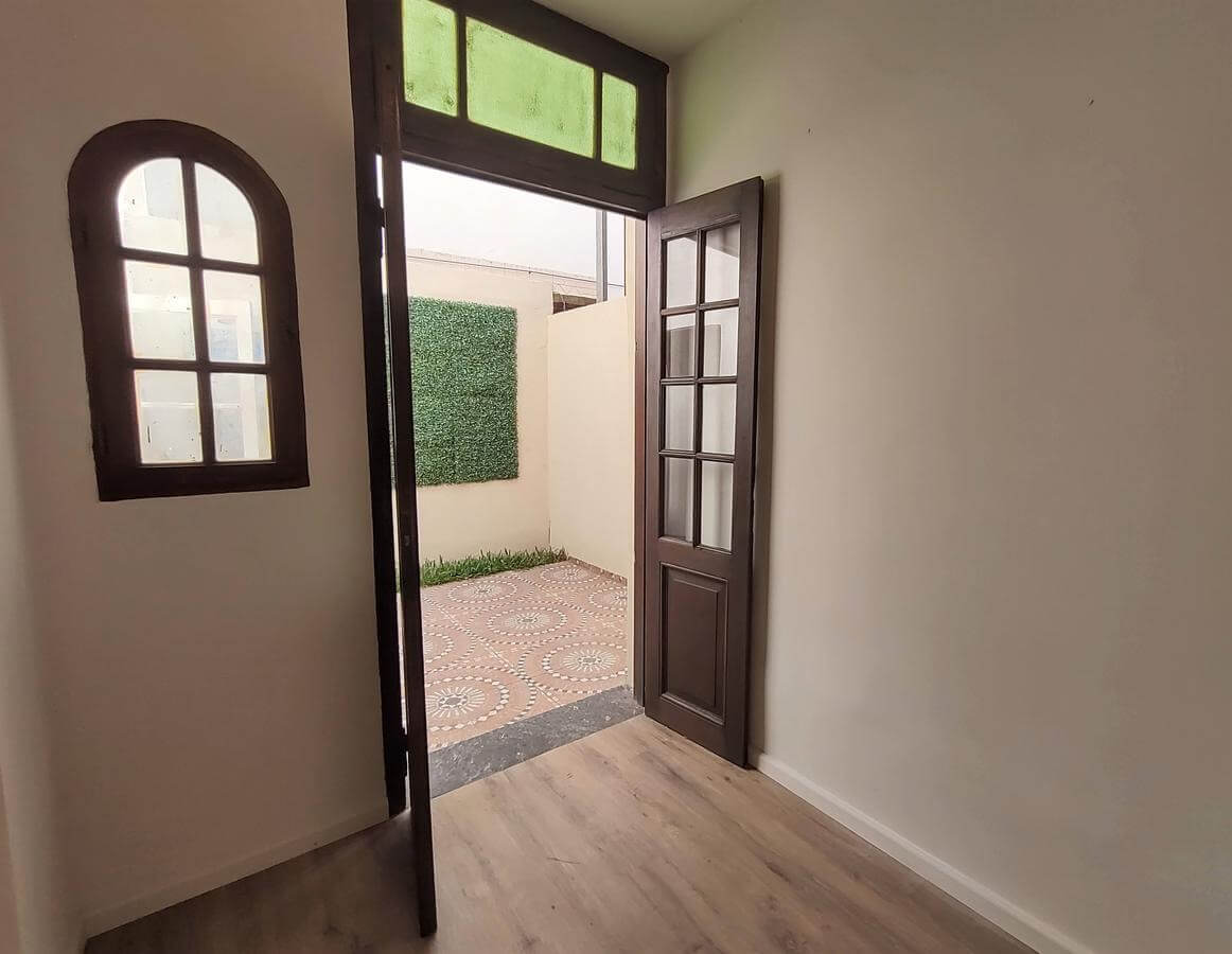 Habitación con puerta de madera hacia el patio.