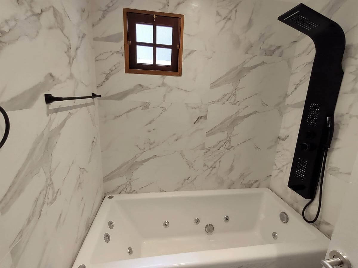 Baño con revestimiento tipo marmol y ducha moderna.