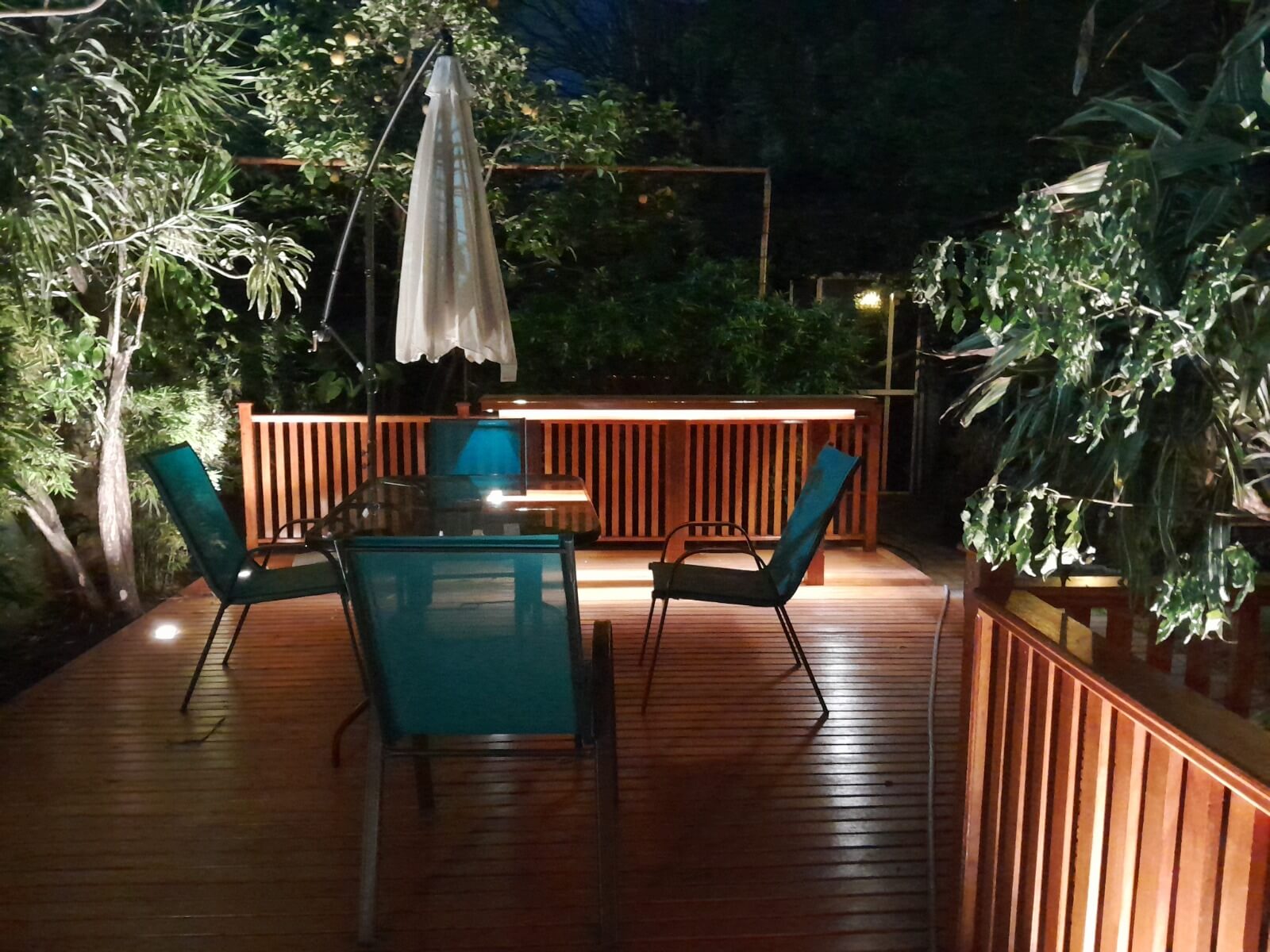 Deck de madera con barra integrada iluminada de noche.