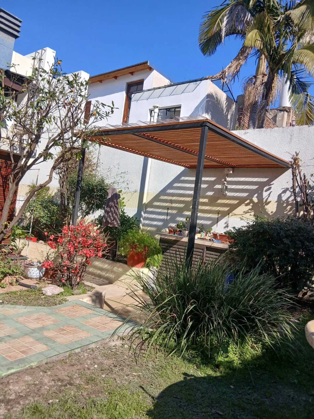 Jardin con pergola de madera.